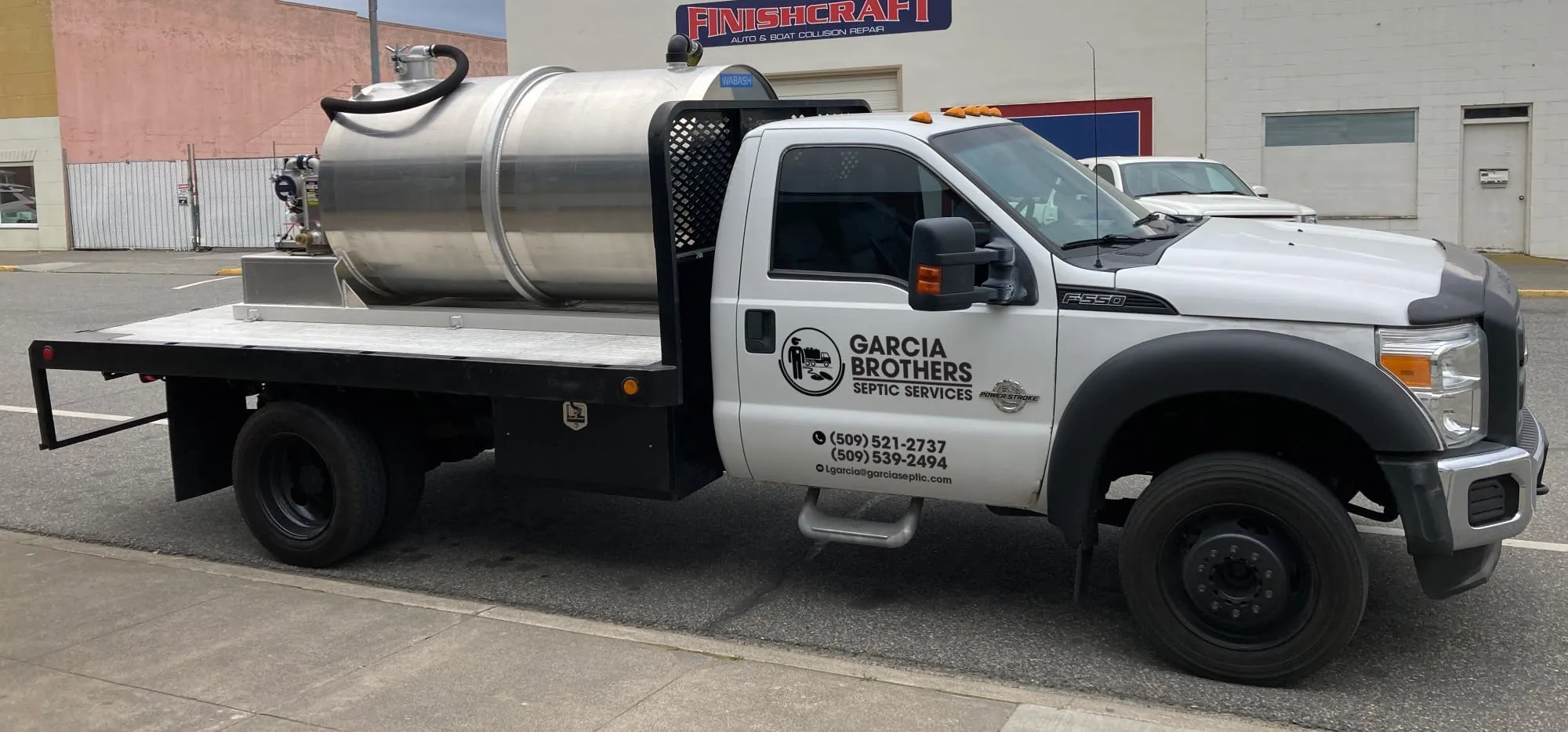 The Garcia Brothers Septic Services white flatbed truck fitted with a polished stainless-steel vacuum tank, branded with the company logo and phone number